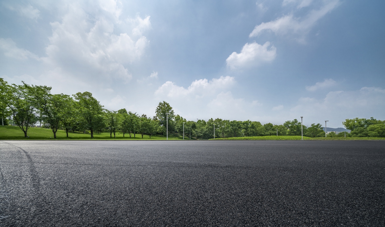 asphalt parking lot surrounded by trees