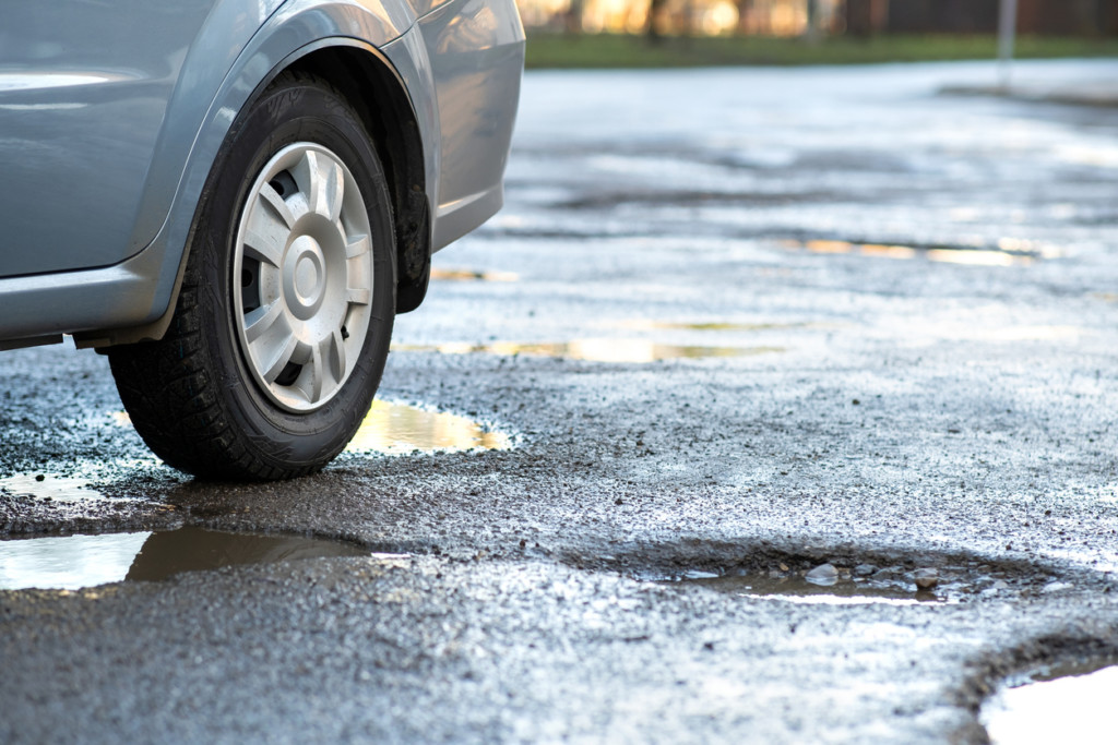 car parked on wet, potholed asphalt