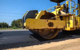 yellow asphalt roller truck on a newly paved road
