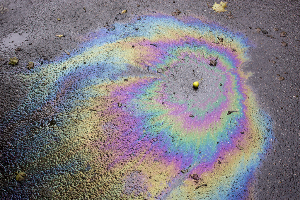 Iridescent spot of oil on asphalt