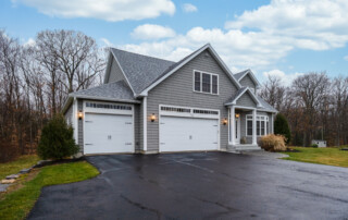 A gray-walled suburban house with asphalt driveway