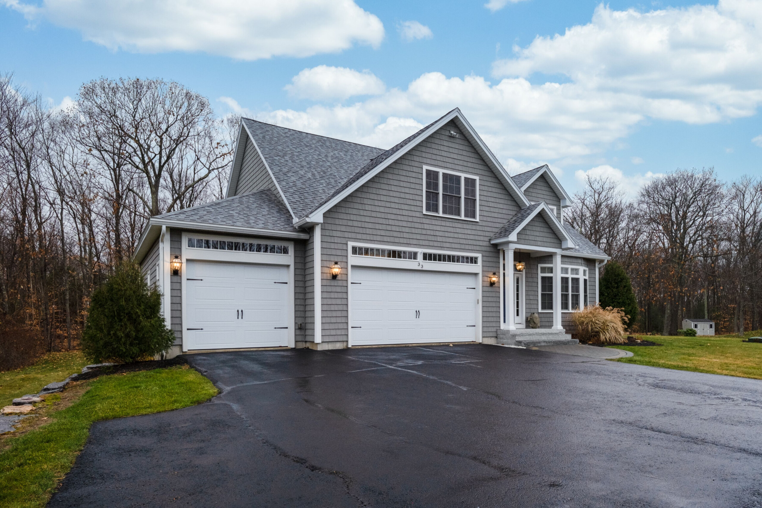 A gray-walled suburban house with asphalt driveway