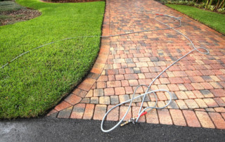 paver driveway with a hose and wand on the driveway.