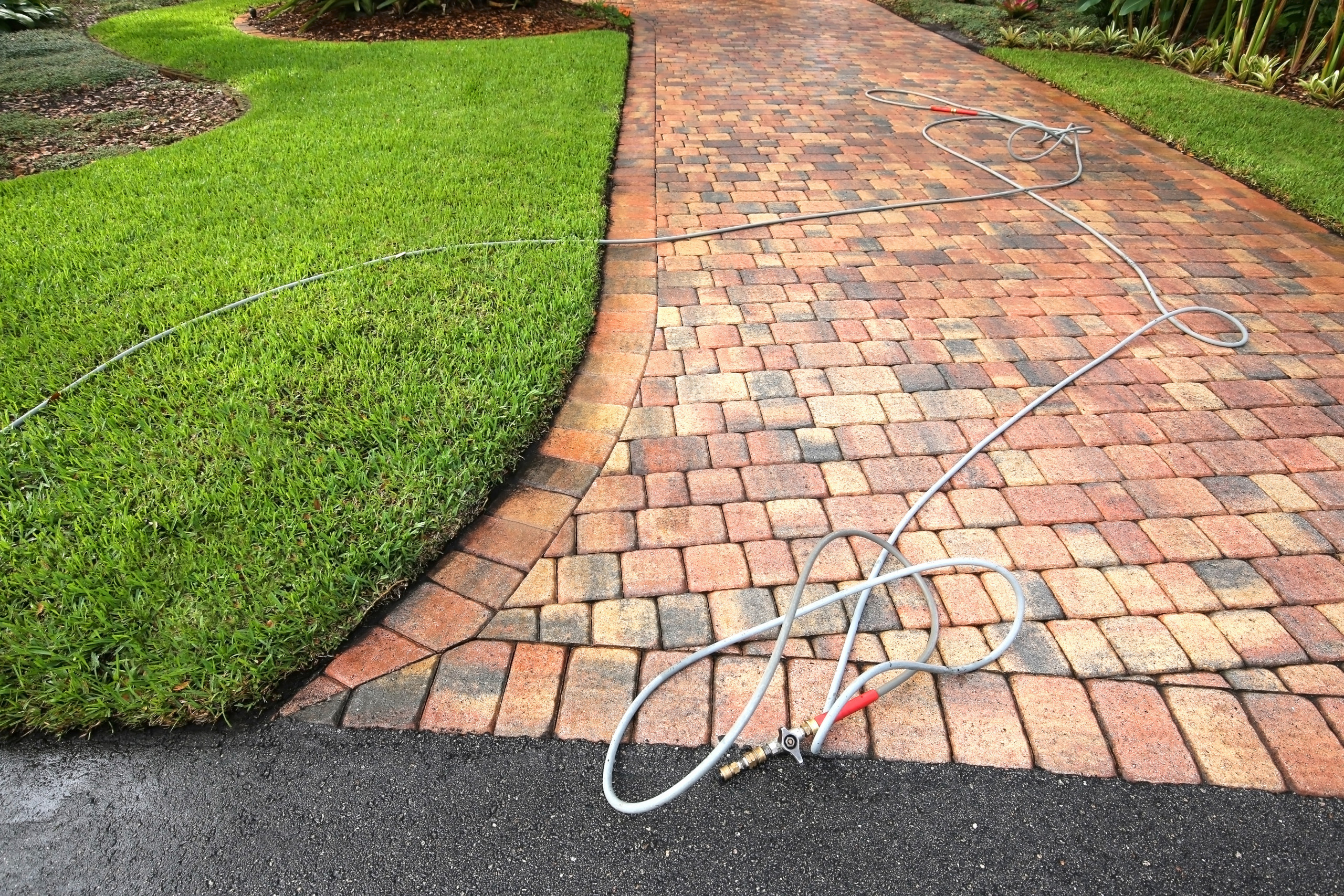 paver driveway with a hose and wand on the driveway.