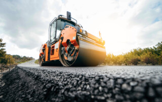 An asphalt paver smoothing out fresh asphalt.