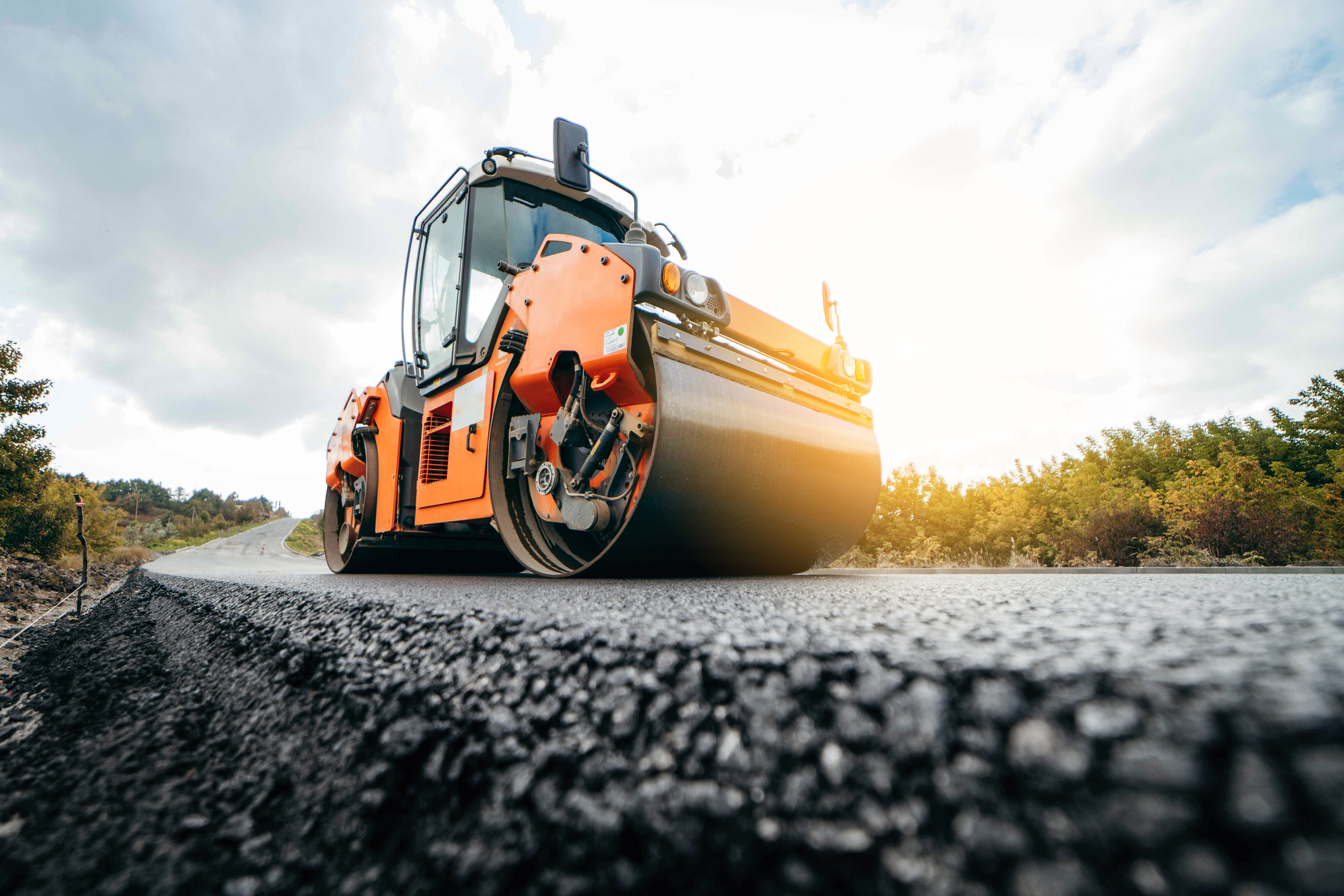 An asphalt paver smoothing out fresh asphalt.