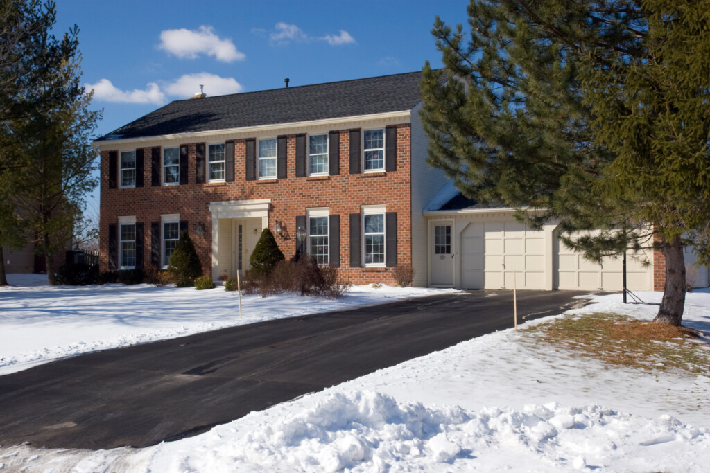 residential grade asphalt driveway next to a large colonial home