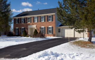 residential grade asphalt driveway next to a large colonial home