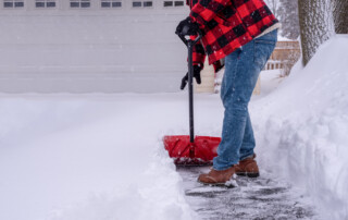a person removing snow and ice from an asphalt driveway