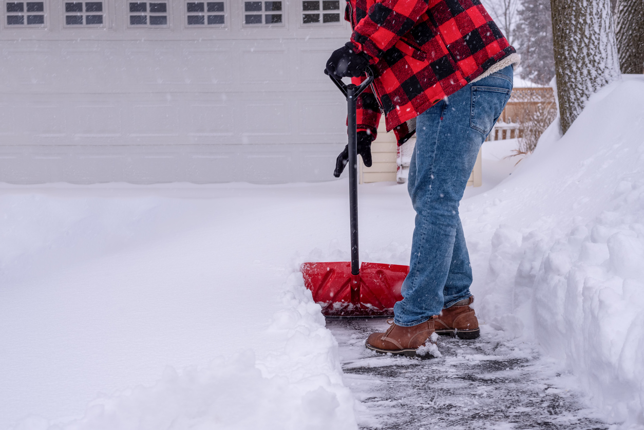 a person removing snow and ice from an asphalt driveway