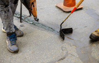 Road surface restoration work in the worker performs road patcher work repair of cracks by filling and sealing with coated by bitumen emulsion asphalt surface