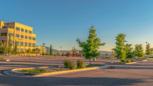 Panorama of a contemporary office building with parking lot on a sunny day. Mountain and sky is in the background of the commercial building.