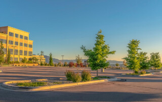 Panorama of a contemporary office building with parking lot on a sunny day. Mountain and sky is in the background of the commercial building.